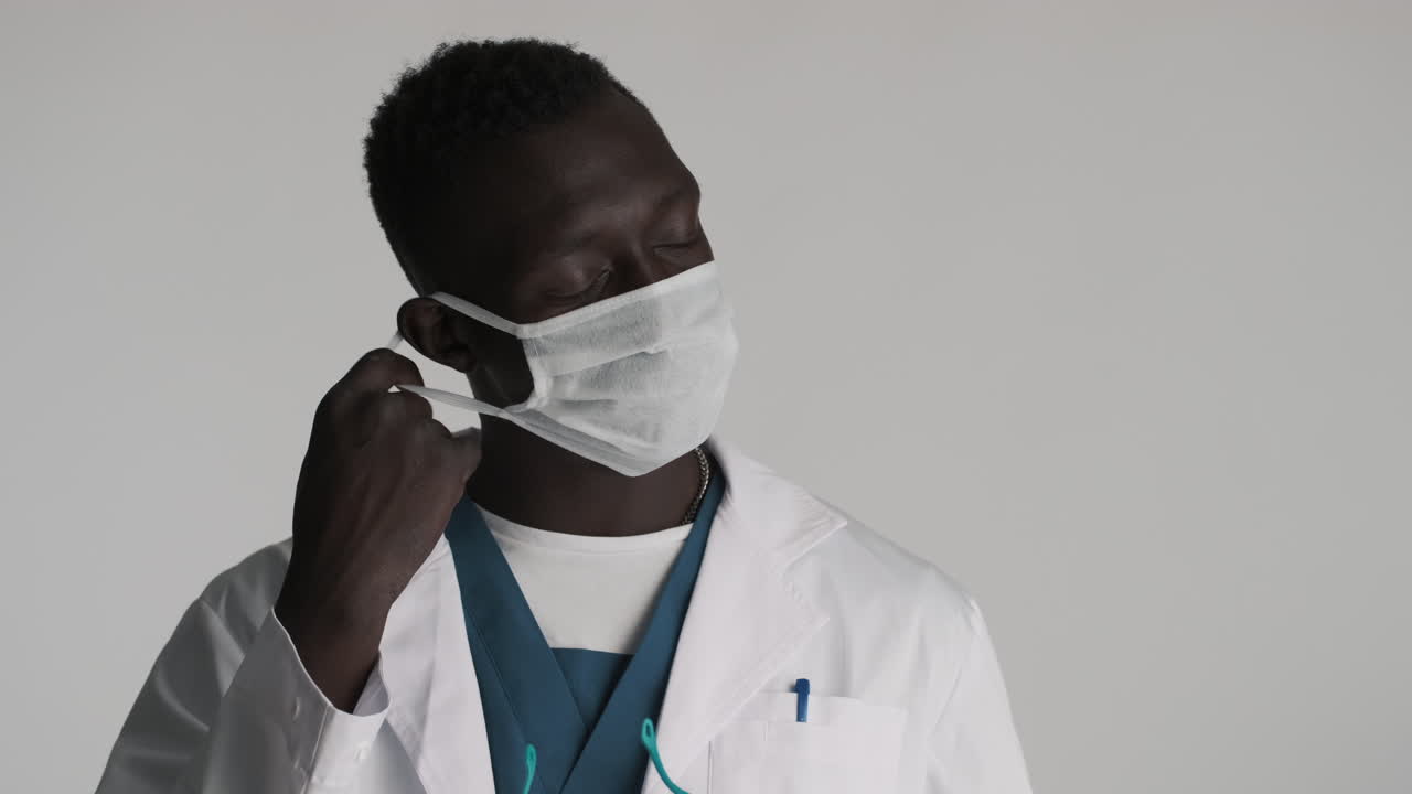 Tired African american doctor on grey background.