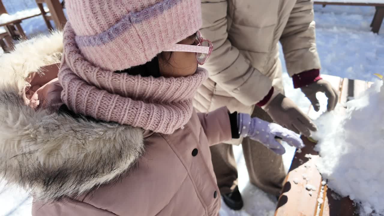 Bambina che gioca con la neve in una soleggiata giornata invernale