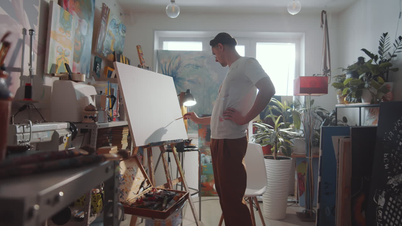 Artista masculino dibujando un cuadro en lienzo en un estudio