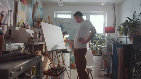 male artist drawing picture on canvas in studio