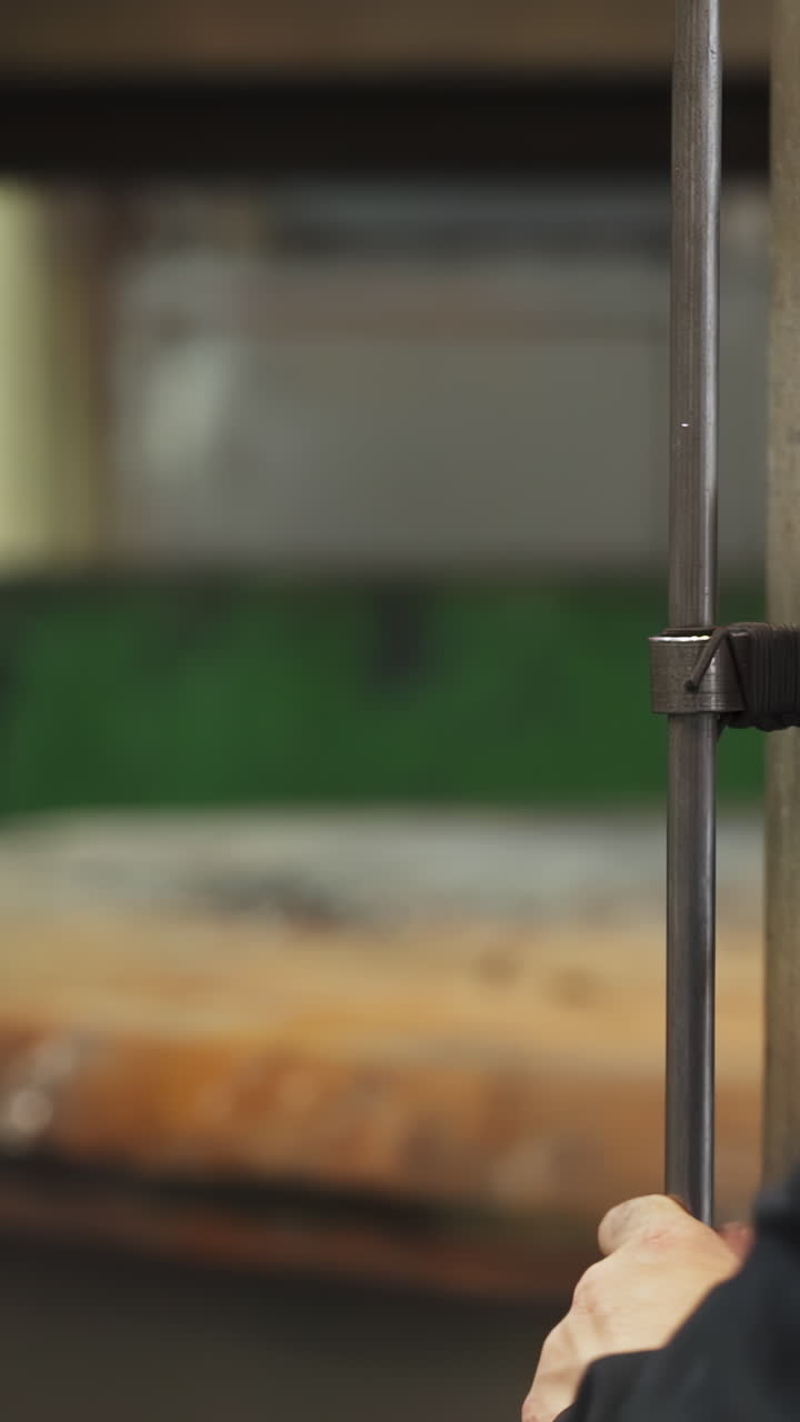 Close-up of a hand working with a metal rod in a workshop