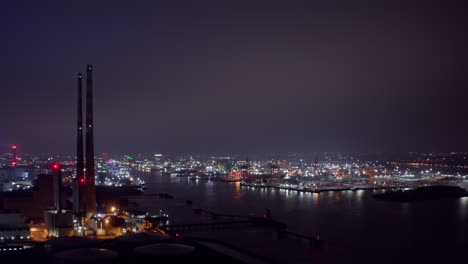 la central eléctrica de poolbeg apila luces parpadeantes con grúas del puerto de dublín y luces de la ciudad por la noche.