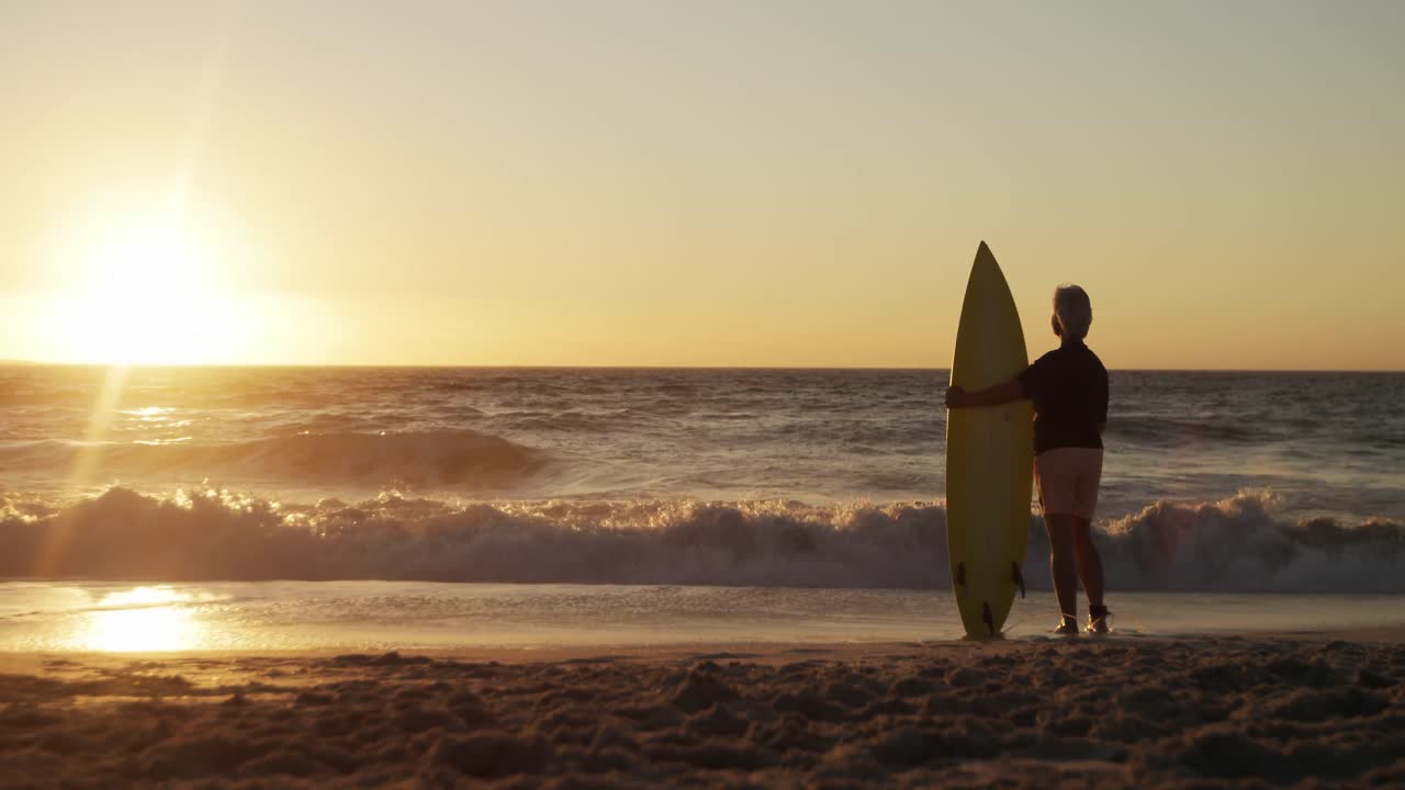 mujer mayor con tabla de surf en la playa