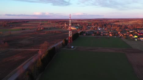 drone volando hacia la torre de comunicación en el campo al atardecer
