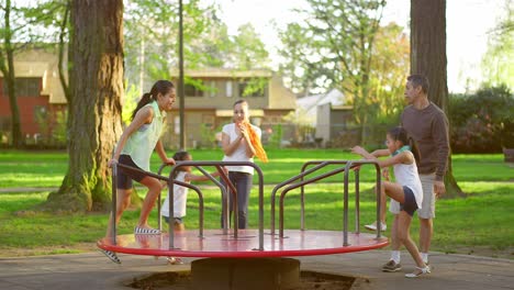 family playing on a merry-go-round at a park