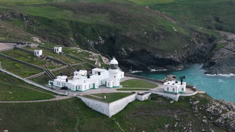 approaching aerial flyover of pendeen lighthouse perched on cornish sea cliffs