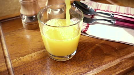 Jugo-De-Naranja-Vertido-En-Un-Vaso,-El-Desayuno-De-La-Mañana.-Cámara-Lenta-Con-Seguimiento-De-Rotación.