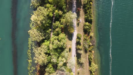 Luftaufnahme-Eines-Radfahrers,-Der-Auf-Einem-Von-Wasser-Umgebenen-Feldweg-Fährt