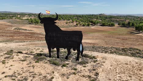 aerial drone view of a huge billboard bull with the spanish flag waving in its head