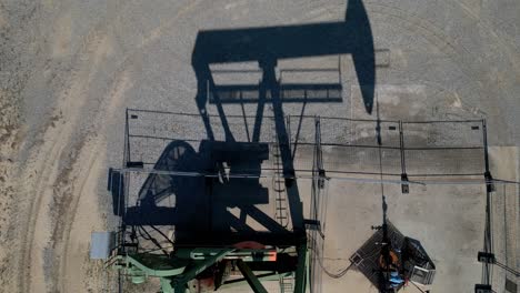 oil pumping jack on desert sands in summer - aerial top down