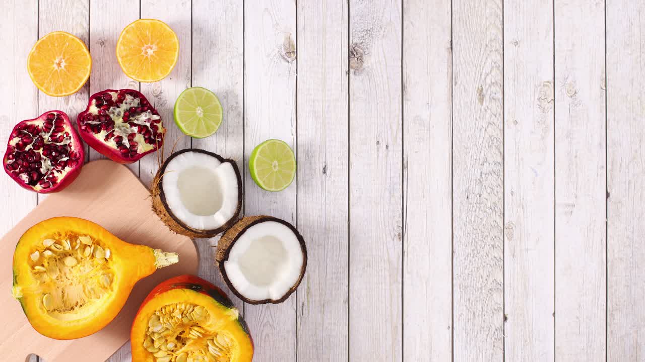 Frutta tropicale e agrumi a fette si muovono sul lato sinistro di uno sfondo in legno. Stop motion.