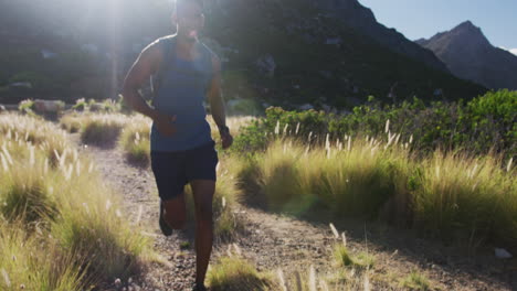 Hombre-Afroamericano-Corriendo-A-Campo-Traviesa-En-El-Campo-En-Una-Montaña