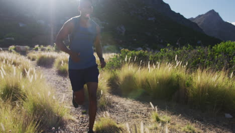 hombre afroamericano de cross country corriendo en el campo en una montaña