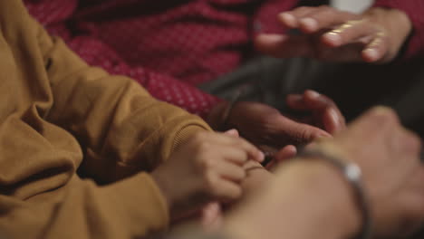 primer plano de una familia sikh masculina de varias generaciones usando y discutiendo brazaletes o pulseras tradicionales de plata sentados en el sofá en casa filmado en tiempo real