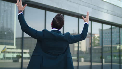 Closeup-businessman-spinning-at-street.-Man-raising-hands-above-at-city-center