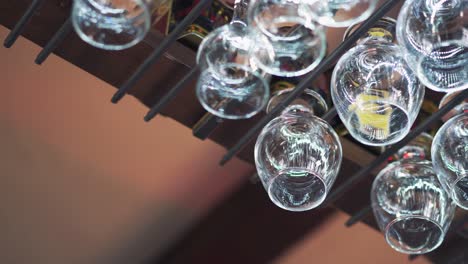 empty clean wine glasses hanging above a bar rack. man's hand takes one crystal glass from a metal rack. close-up