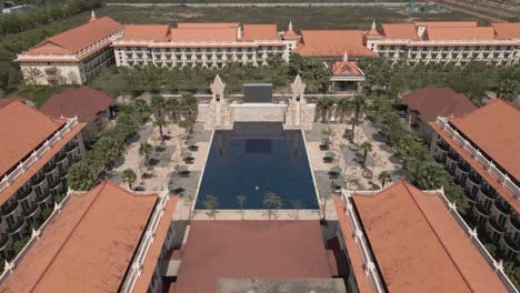 Wide-aerial-descends-to-lone-swimmer-in-huge-resort-pool,-Siem-Reap