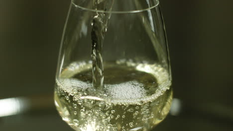 close up shot of white wine being poured in a wine glass