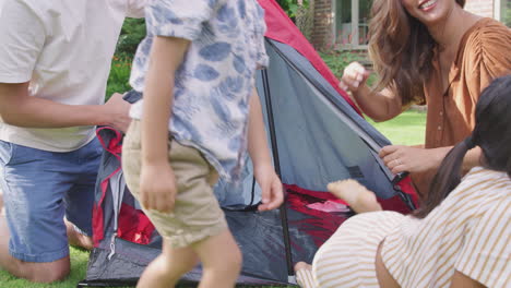 niños escondiéndose en la tienda de campaña como padres asiáticos ponerlo en el jardín en casa para el viaje de acampada de verano