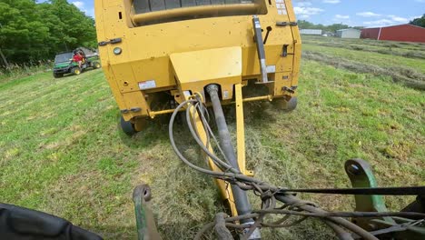 vista del punto de enganche entre el tractor y la empacadora de heno mientras se remolca la empacadora a lo largo de la hilera de alfalfa