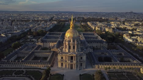 a drone shot pulls back to reveal a setting sun shining on the dome church in paris, france