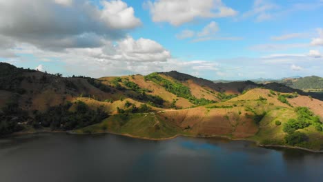 pull out aerial reveal shot of a panoramic mountain view with cloudy blue sky