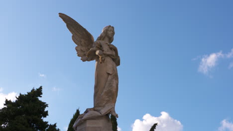 statue of an angel with clouds timelapse in the background