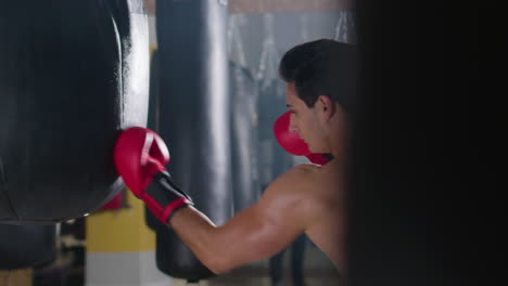 young male boxer hitting punching bag in gym