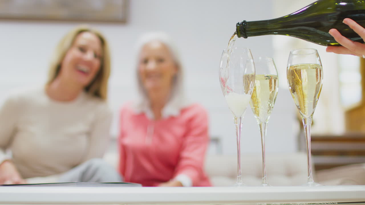 Primo piano di champagne o prosecco versato in bicchieri con due donne sullo sfondo