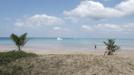 la playa con algunos yates en el mar, arena blanca y olas de un mar tranquilo durante el día soleado