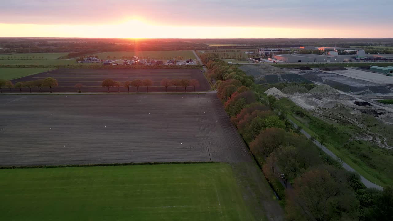 Luftfoto af marker og industriområde ved solnedgang