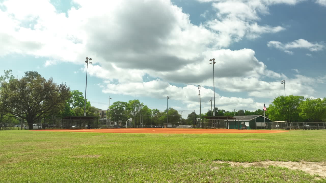 Inquadratura aerea con tilt-up su erba e campo da baseball di una scuola in America durante una giornata nuvolosa.