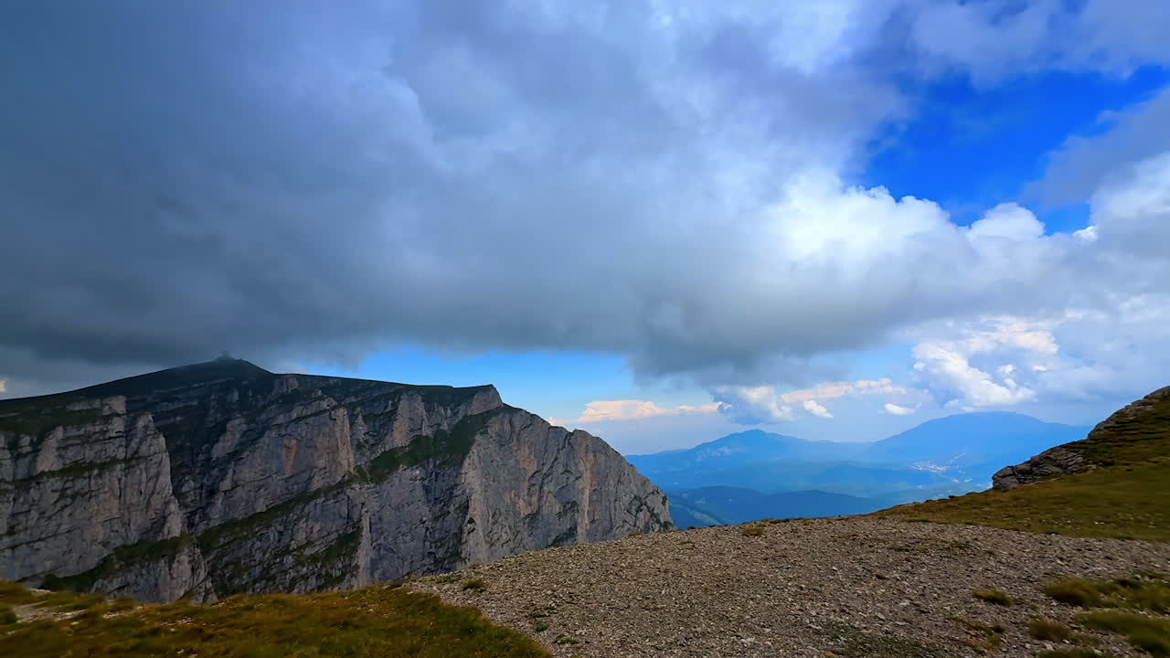 Walking up to the edge of the rock. Spectacular scenery of the mountains against cloudy sky