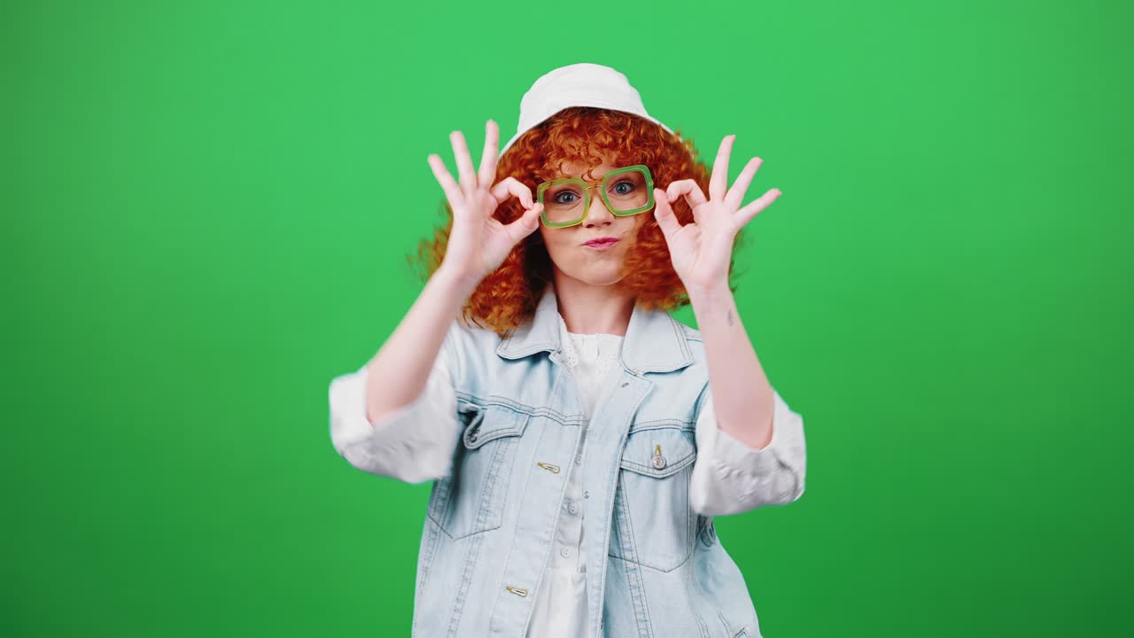 está bien. joven, fresca, alegre, pelirroja, mujer rizada con sombrero de panamá y gafas que muestran bien con ambas manos.