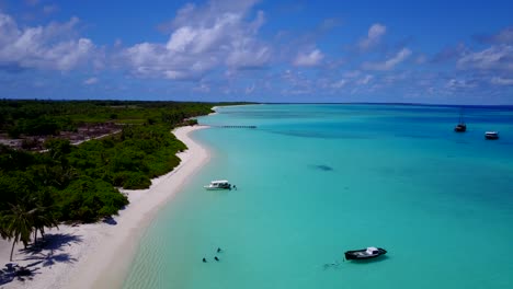 aerial view of a carribean island as the drone traces on the white sandy beach as the turquoise water hit the shores