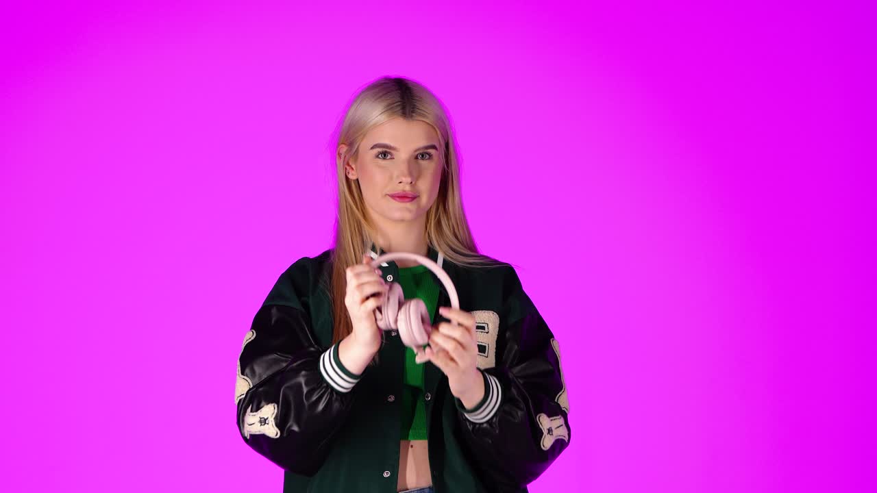 joven rubia alegre escuchando música con auriculares, bailando y el pulgar hacia arriba gesto