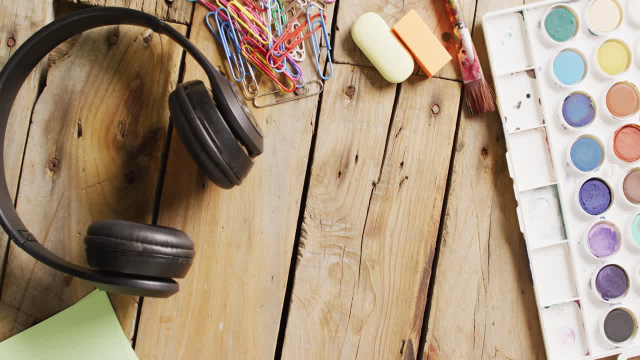 vídeo de pinturas de acuarela, auriculares y artículos de papelería en tableros de madera con espacio para copiar