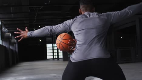 hombre y mujer afroamericanos de pie en un edificio vacío jugando al baloncesto
