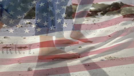 people walking on beach with us flag waving and constitution foreground