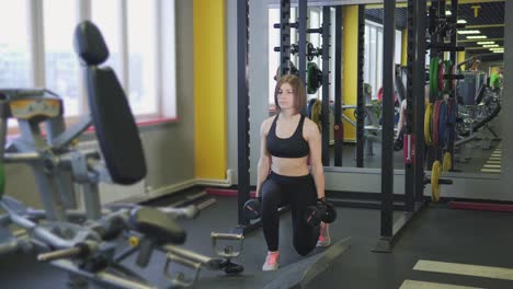 woman doing dumbbell lunges in gym