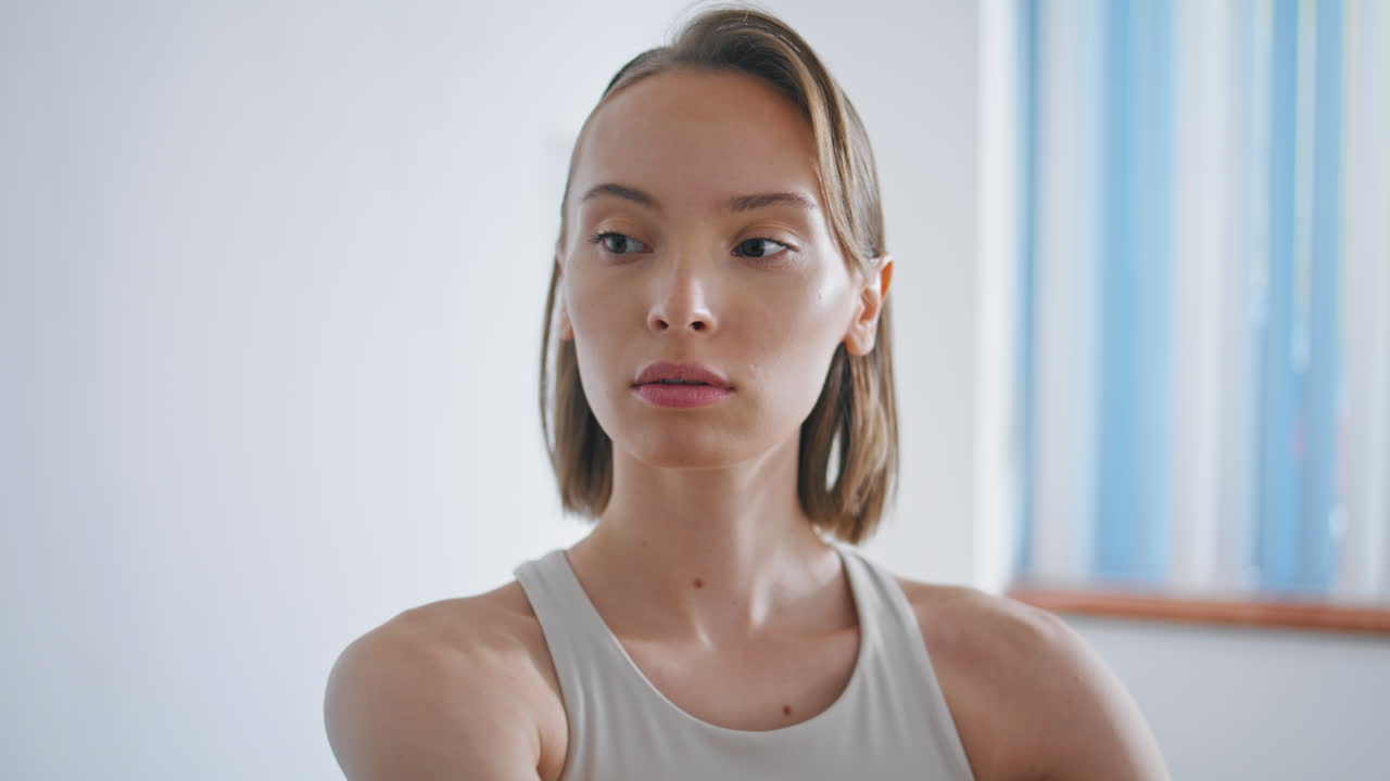 chica enfocada calentando el cuerpo interior blanco primer plano. modelo de atleta estirando las manos