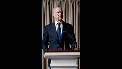 man in formalwear speaking at a podium