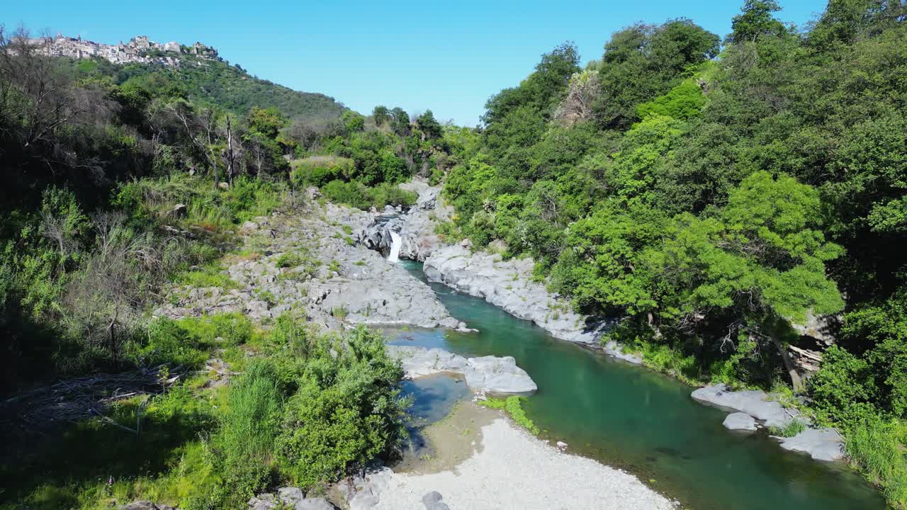 Aerial drone footage of the Alcantara River, Sicily: flowing water, small cascades, rocks and green riverbanks. Perfect for nature, travel and scenic landscape projects
