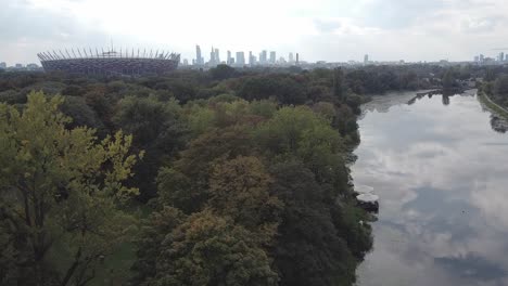 beautiful drone revealing shot of warsaw national stadium of poland, city and lake in the background