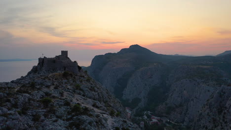 starigrad fortress on omis clifftop, croatia, sunset aerial reveal