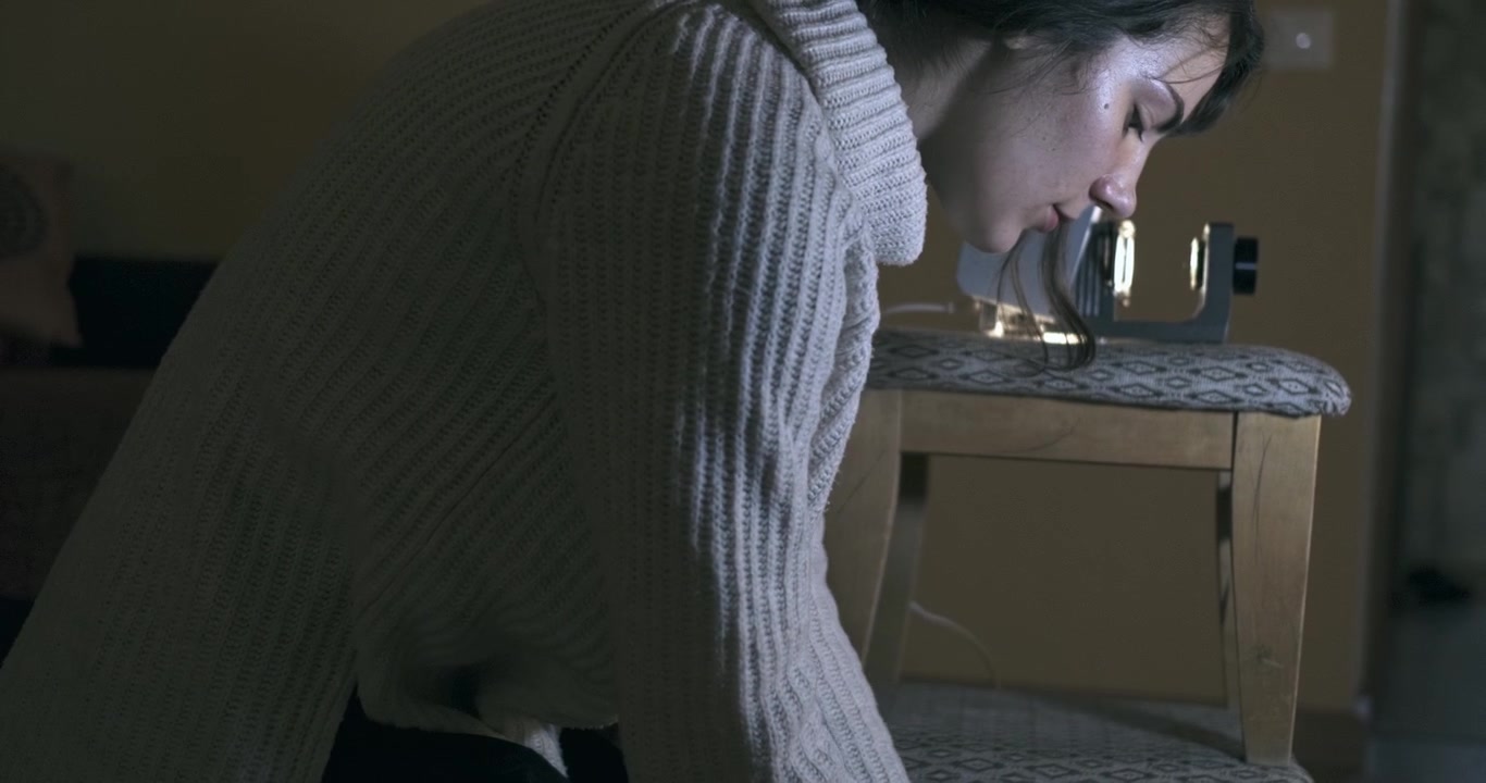 A Woman Looks Through Photographic Slides, Projector In Background.