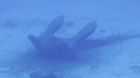 Cinematic-close-up-dolly-shot-of-a-ship-anchor-on-the-ocean-floor-through-a-submarine-porthole-off-the-coast-of-the-island-of-Hawai'i