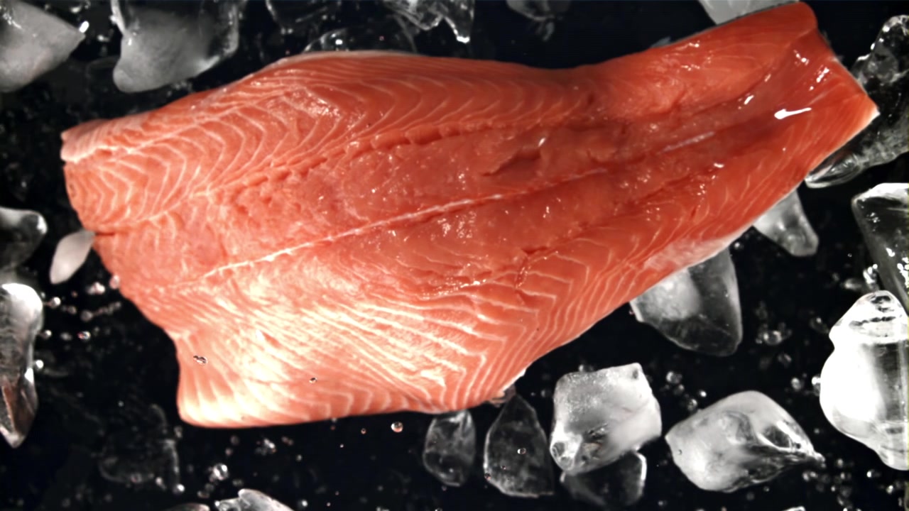 Primo piano di filetto di salmone fresco su ghiaccio con goccioline d'acqua