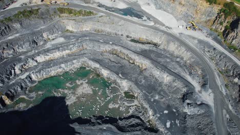 open cast mine deep sides and roads leading to the bottom of the workings with deep green lake
