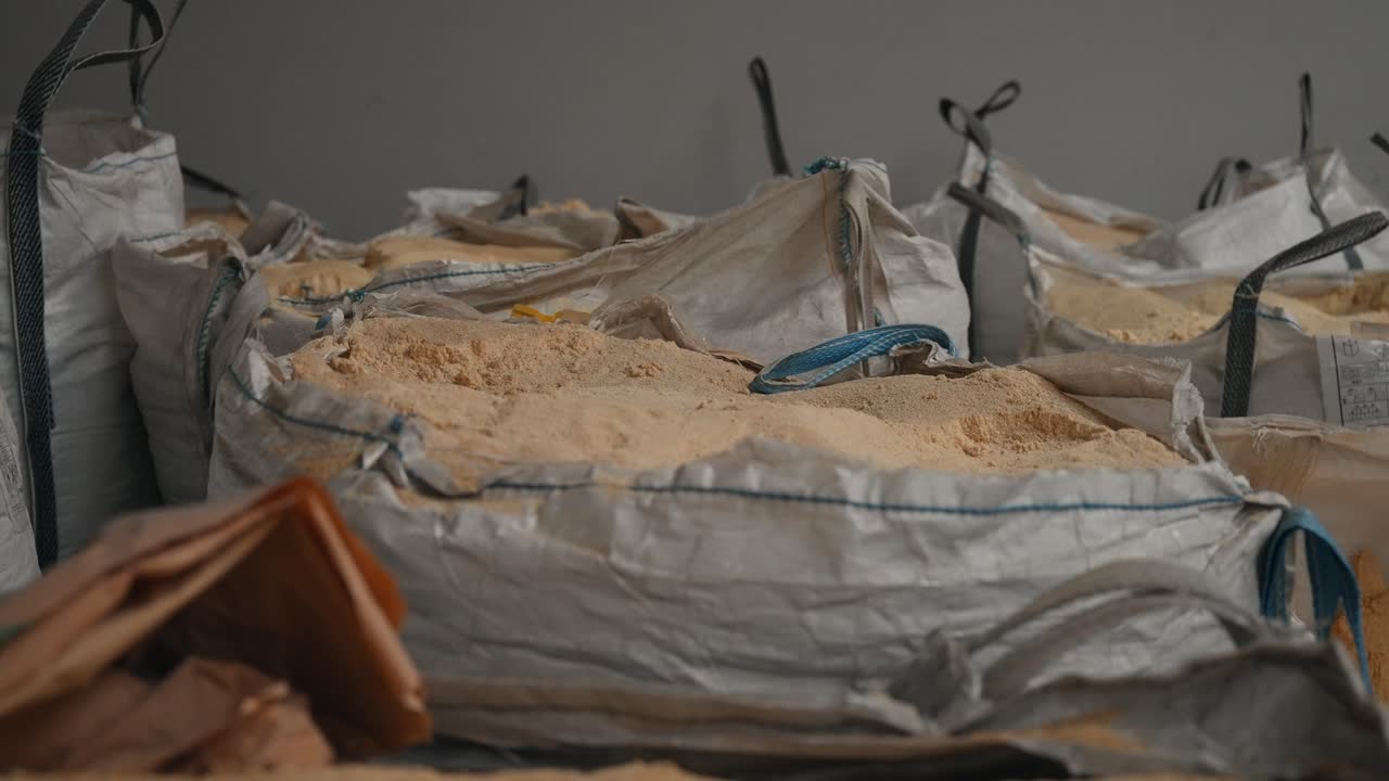 Big bags filled with processed rubber powder inside a recycling factory storage area